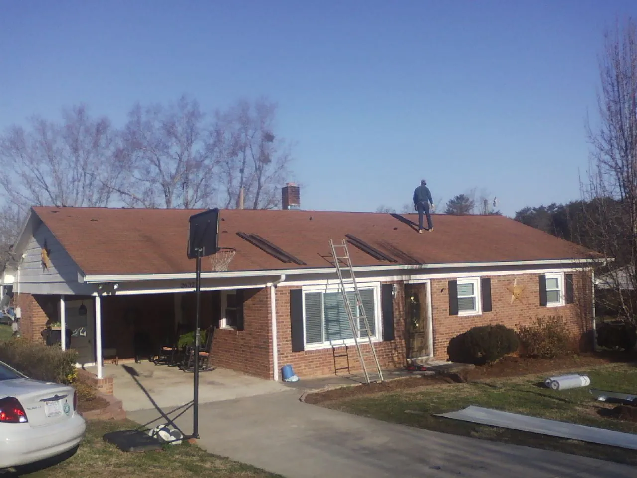 Roofer stripping a shingle roof on a brick ranch before metal panels in Simonton