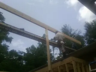 Carpenter setting a ridge beam over a new addition frame — Ice Dam Removal by Roofing Brothers in Simonton