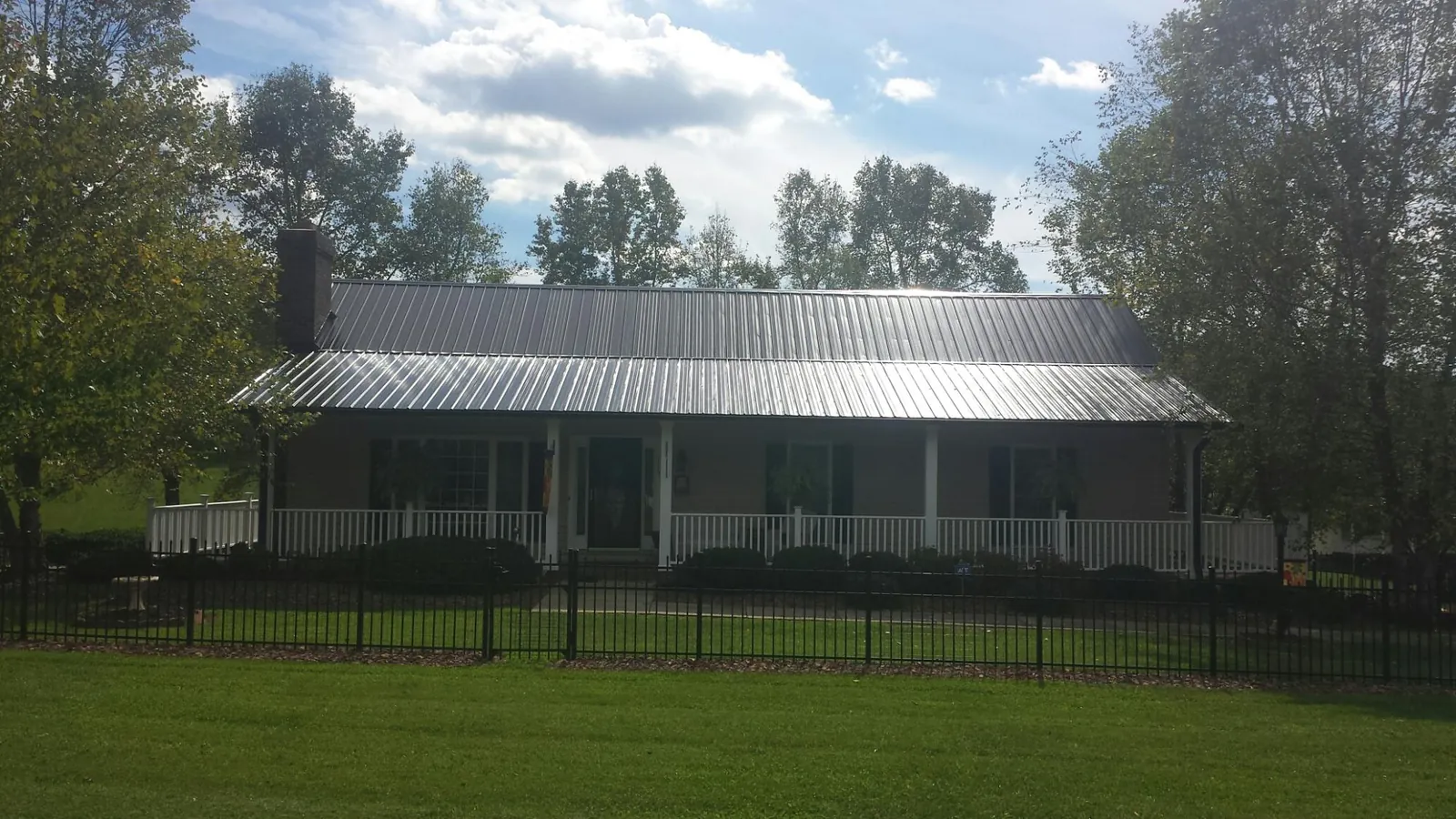 Gray metal roof on a brick ranch with a full width front porch — Gutter Guard Installation work by our crew in Simonton