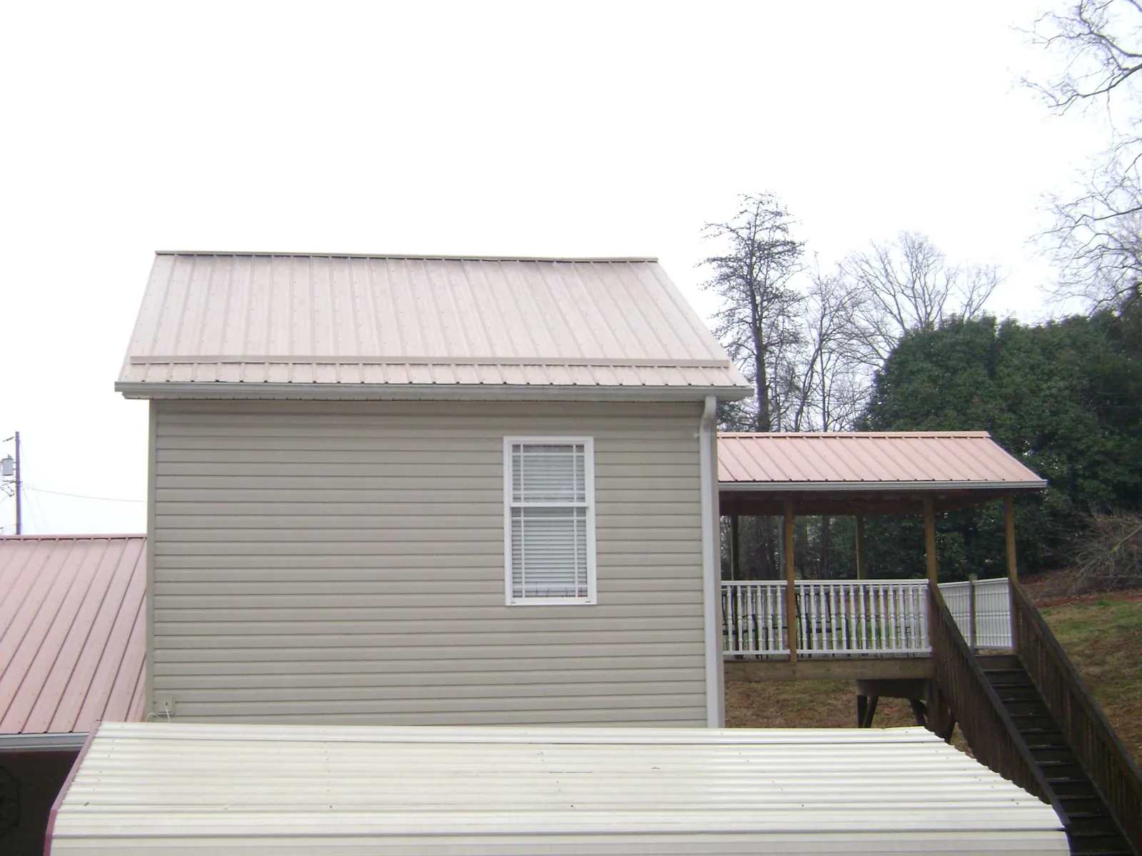 Tan metal roofs on a two story addition and attached porch, from a Roof Replacement job in Simonton